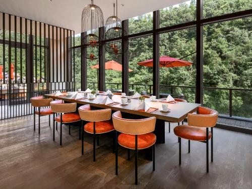 a dining room with a long table and chairs and windows at Ahn Lan Xinchang in Xinchang