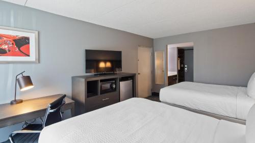 a hotel room with two beds and a desk and a television at Best Western Carlisle South in Carlisle