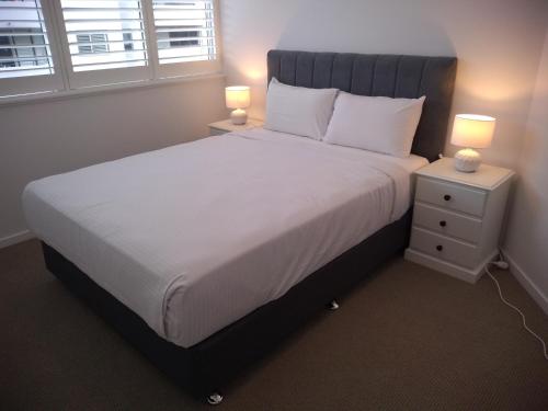 a bed with a white comforter and white pillows at Chasely Apartment Hotel in Brisbane