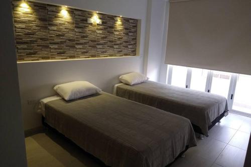 two beds in a hotel room with lights on the wall at Hermoso y amplio apartamento con garaje en San Gil in San Gil