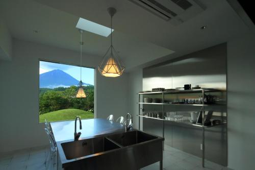 uma cozinha com um lavatório e vista para uma montanha em abrAsus hotel Fuji em Narusawa