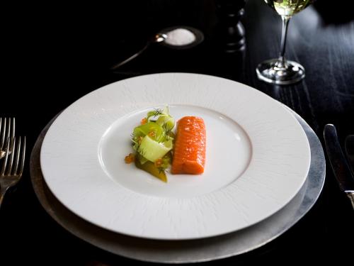 a plate with a carrot and vegetables on a table at Huka Lodge in Taupo