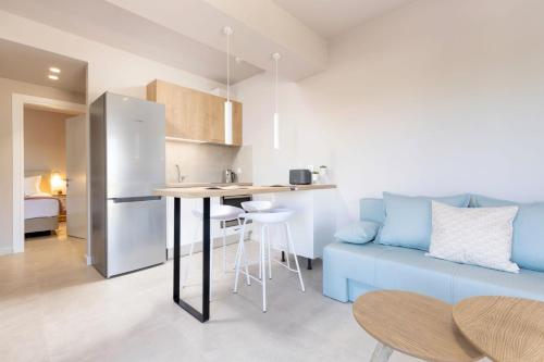 a kitchen and a living room with a blue couch at Onore Luxury Suites in Kato Korakiana