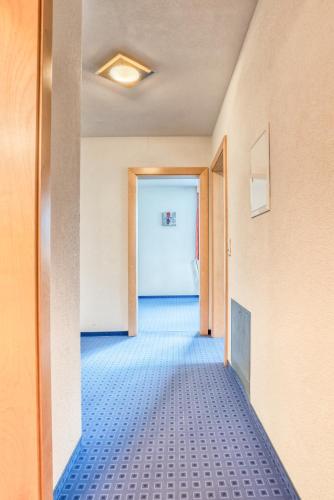 an empty hallway with blue tile floors and a door at Appartementhaus Sonneck in Imst
