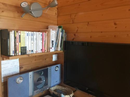 Cette chambre dispose d'une télévision et d'une étagère avec des livres. dans l'établissement Appartements duplex dans chalet - Pléiades -, skis aux pieds avec clefs à disposition via agence constel'immo -nous louons aussi le second duplex du chalet quasiment identique, à Risoul