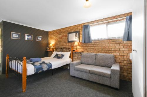 1 dormitorio con 1 cama y 1 silla en Cunningham Shore Motel, en Lakes Entrance