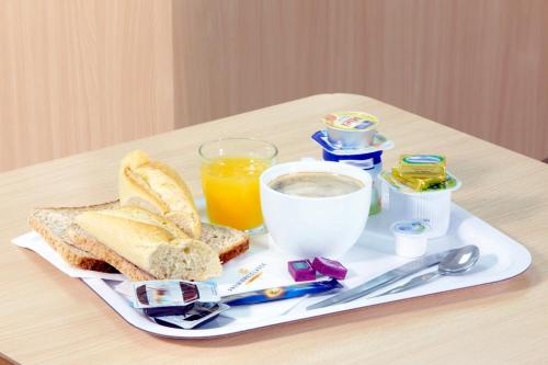 a breakfast tray with toast and a glass of orange juice at Premiere Classe Montbeliard - Sochaux in Sochaux