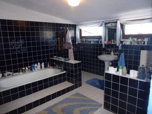 baño de azulejos azules con bañera y lavamanos en Dom z Ogrodem Darłowo do 10 osób !, en Darłowo
