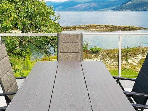 a wooden table with two chairs and a view of the water at Seaside Serenity in Hardangerfjord-By Traum in Tyrvikbygd