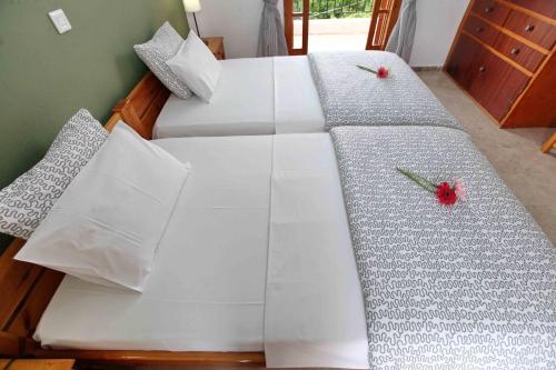 a white bed with two red flowers on it at Sofia Apartments - Kantia in Kandia