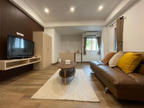 een woonkamer met een bank en een tv bij Pimann Place Hotel in Chiang Rai