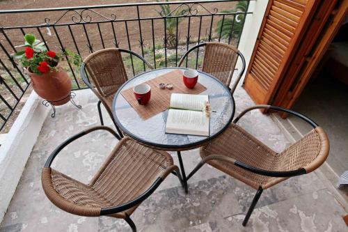 a table with two chairs and a book on a balcony at Sofia Apartments - Kantia in Kandia