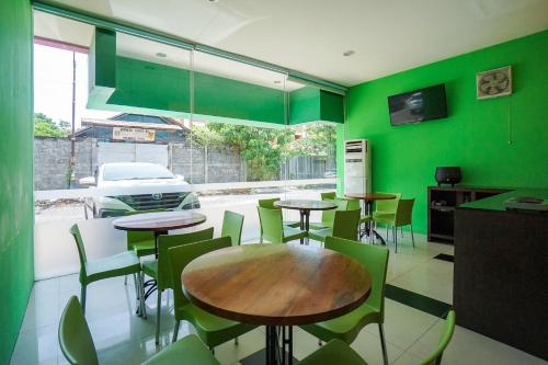 a restaurant with green walls and tables and chairs at OYO 770 De Nearby Hotel in Manado