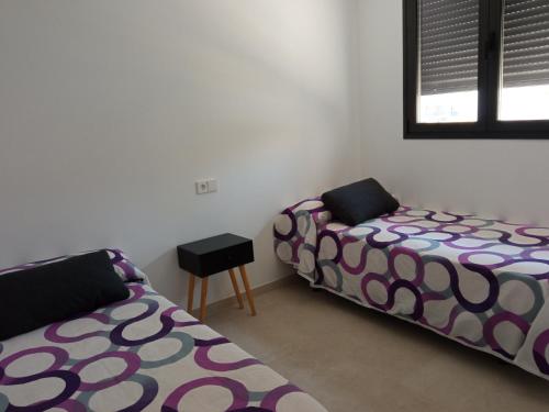 ガンディアにあるPlaya Gandía Residencial Álamoのベッド2台とテーブルと窓のある部屋