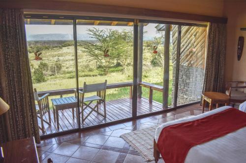 Lake Nakuru Lodge في ناكورو: غرفة بسرير وشرفة مطلة