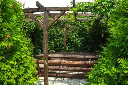 a wooden bench sitting under a pergola in a garden at Fazenda in Sumy