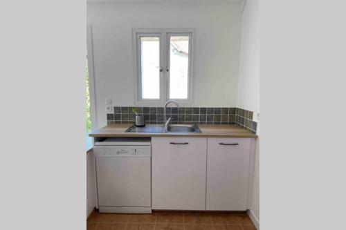 cocina blanca con fregadero y ventana en Chez Pat&Fred, en Balnot-la-Grange
