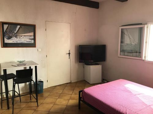 une chambre avec un lit, une table et une télévision dans l'établissement Chambre climatisée avec sdb privée dans une villa avec piscine ouverte d'avril à mi octobre, à Marseille