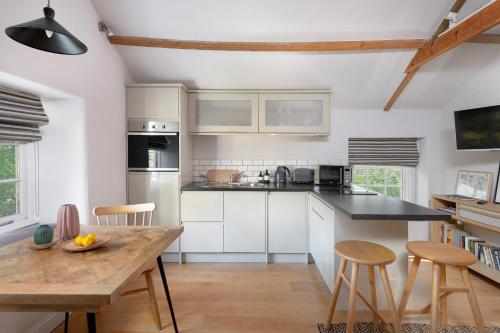 uma cozinha com armários brancos e uma mesa de madeira em The Hayloft by Black Door Stays em Bath