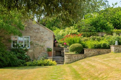 a stone house with a garden with flowers at The Hayloft by Black Door Stays in Bath