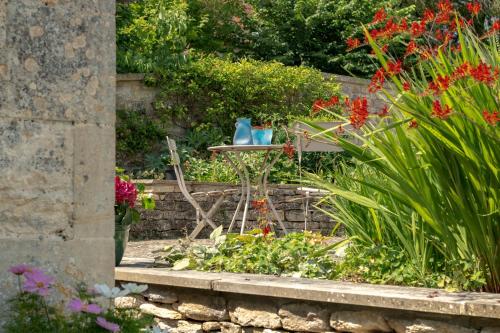 a garden with flowers and a table with two blue vases at The Hayloft by Black Door Stays in Bath