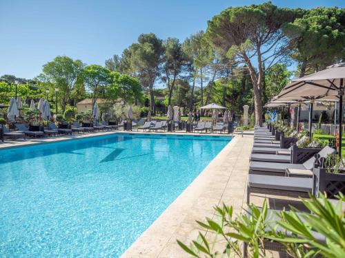 a swimming pool with lounge chairs and umbrellas at Le Vallon de Valrugues & Spa in Saint-Rémy-de-Provence