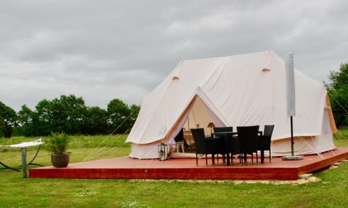 a tent with a table and chairs in a field at Pension Lærkelill in Skovlund