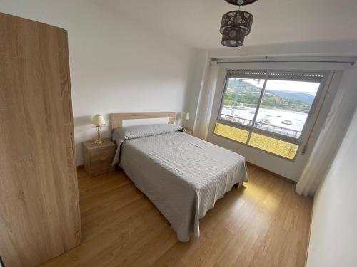 um quarto com uma cama e uma grande janela em Apartamento céntrico con vistas y cerca de playa em Puentedeume