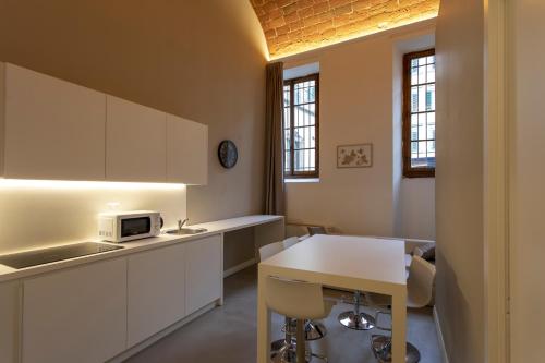 a kitchen with white cabinets and a table with a microwave at Palazzo dei Ciompi Suites in Florence