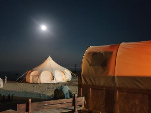 a tent in the desert at night with the moon at Badolina Ein Gedi Glamping in Ein Gedi