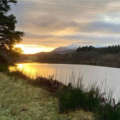 a sunset over a lake with a mountain in the background at Loch Ness Pods in Fort Augustus