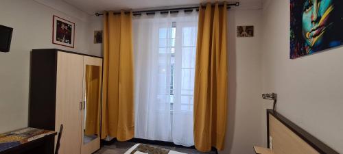 Cette chambre dispose d'une fenêtre avec des rideaux jaunes. dans l'établissement Hôtel Renova, à Nantes