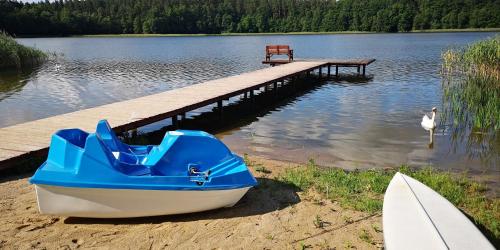 a boat sitting on the sand next to a dock at Apartamenty Mazurskie Klimaty (Cud Natury) in Tomaszkowo