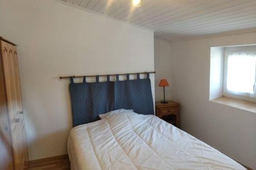 ブワンにあるLA MAISON BLEUEのベッドルーム1室(青いカーテンと窓付きのベッド1台付)