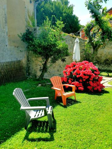 two chairs and a bench in a yard with flowers at Apt duplex ou plain pied tout confort plein centre ville Bayeux proche commerces, restaurants, avec terrasse privative ou jardin commun aménagé clos, parking gratuit à proximité, proche plages du débarquement in Bayeux