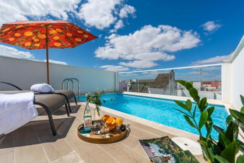 a hotel room with a swimming pool and an umbrella at Casa Triana 1888 Suites by Época in Seville