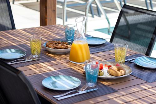 a table with a plate of food and a bottle of orange juice at Cato Agro 1, Seafront Villa with Private Pool in Karpathos Town