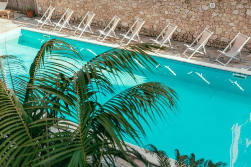 a blue swimming pool with chairs and a palm tree at Hotel Residence La Palma in Finale Ligure