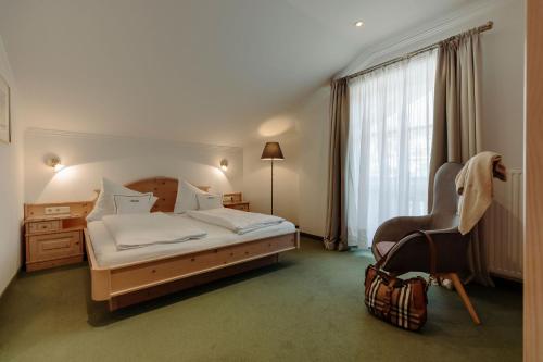 a bedroom with a bed and a chair and a window at Ferienwohnungen Johanneshof in Maria Alm am Steinernen Meer