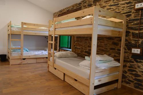 a room with two bunk beds and a brick wall at Eco dos Teixos in Casayo