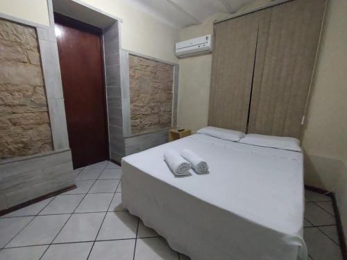 um quarto com uma cama branca e toalhas em Hotel Castelo em Santana do Livramento