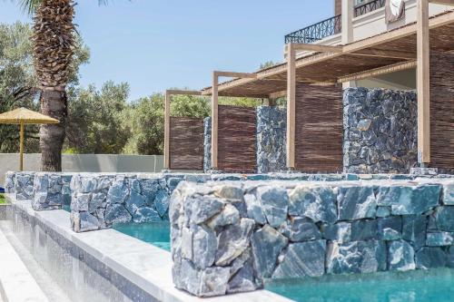 a swimming pool with a rock wall next to a house at Dias Studios & Suites in Faliraki