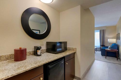 a room with a counter with a tv and a mirror at Comfort Suites Near Universal Orlando Resort in Orlando