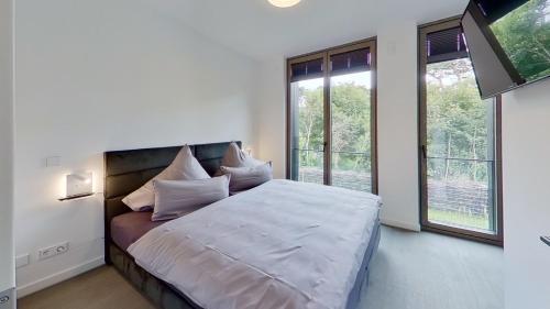 a bedroom with a bed with white sheets and windows at Haus KiefernVier in Norderney