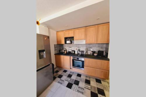 - une cuisine avec des placards en bois et un sol en damier dans l'établissement Saint Raphaël, bel appartement en centre ville !, à Saint-Raphaël