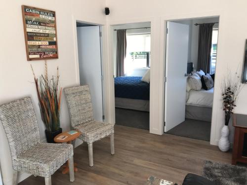 a room with two chairs and a bedroom with a bed at Casa Riveria in Pauatahanui