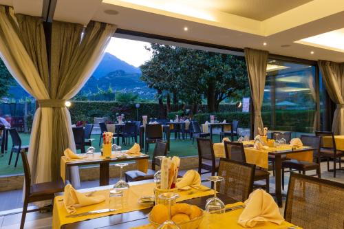 a restaurant with yellow tables and chairs and a large window at Hotel Campagnola in Riva del Garda