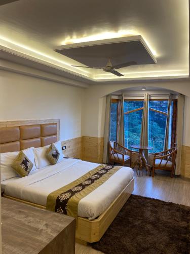a bedroom with a bed and a table and windows at Hotel Silverine in Shimla