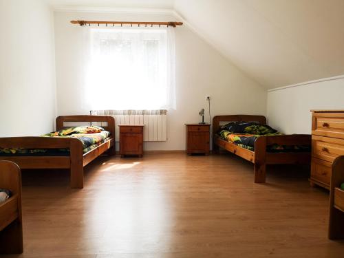 1 dormitorio con 2 camas y ventana en Bieszczadzki dom nad stawem, en Ropienka