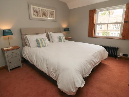 a bedroom with a large white bed with a window at Ascot Cottage in York